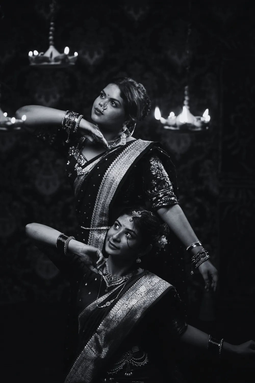 Two classical Indian dancers in traditional costume, photographed in black and white by lamplight
